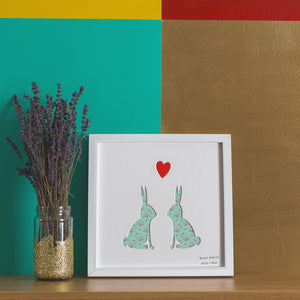 Two rabbits with a heart above their heads artwork with green floral pattern